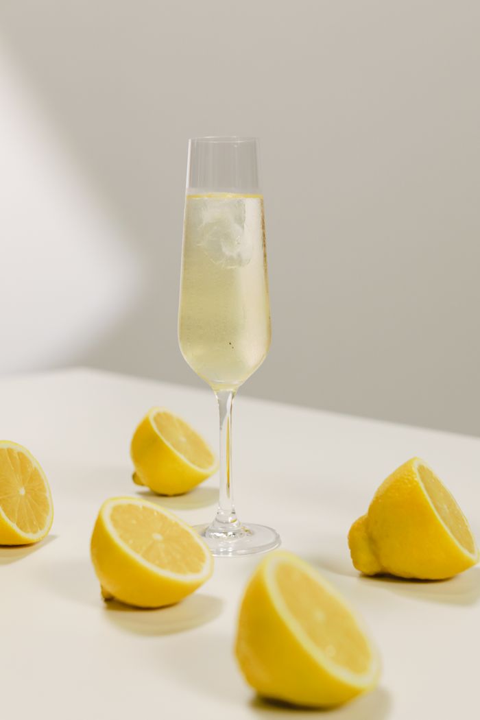 Home Champagne glass with fresh lemon slices on a white table, capturing a refreshing still life.